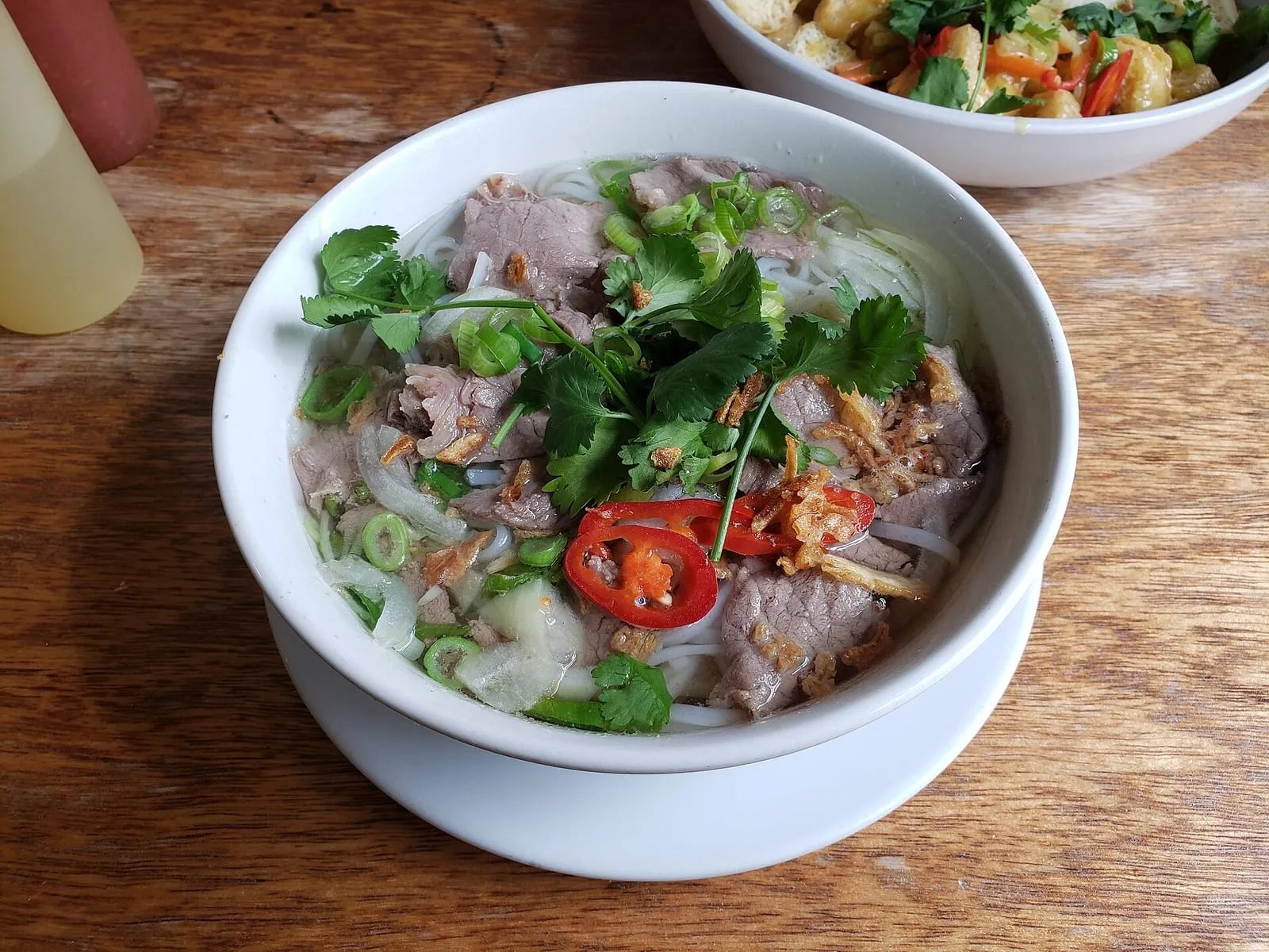 Schale Phở Bò mit Rindfleisch, Koriander und roten Chilis — die vietnamesische Nationalsuppe